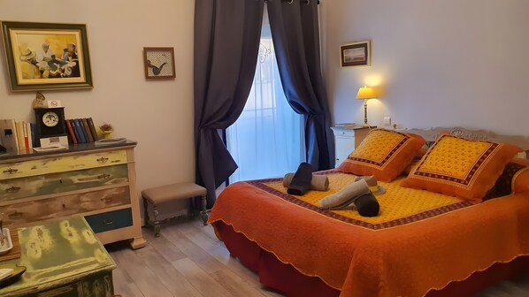 A bedroom with a bed, a nightstand, a dresser, a window with curtains, and a wall clock.