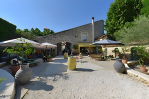Ein Innenhof mit Steinsäulen, Pflanzkübeln und Außenmöbeln.