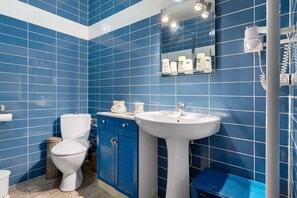 Un baño con azulejos azules, un inodoro blanco, un lavabo y un espejo.