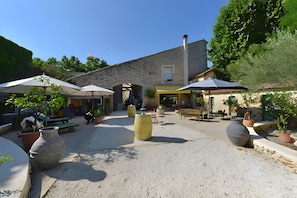 Une cour extérieure avec des murs en pierre, des plantes en pot et des sièges d’extérieur.