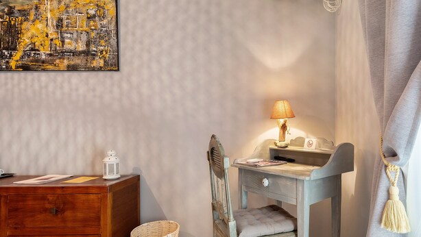 Et værelse med et træskrivebord, en lampe, en stol, en kurv og et billede på væggen.