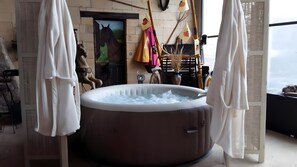 Un bain à remous dans une pièce avec vue, une statue de cheval et une décoration rustique.