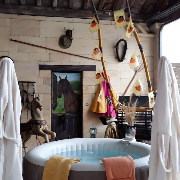 Une pièce ornée d’une statue de cheval, d’une porte sur laquelle est peinte une scène équestre, d’un jacuzzi et de divers éléments décoratifs suspendus.
