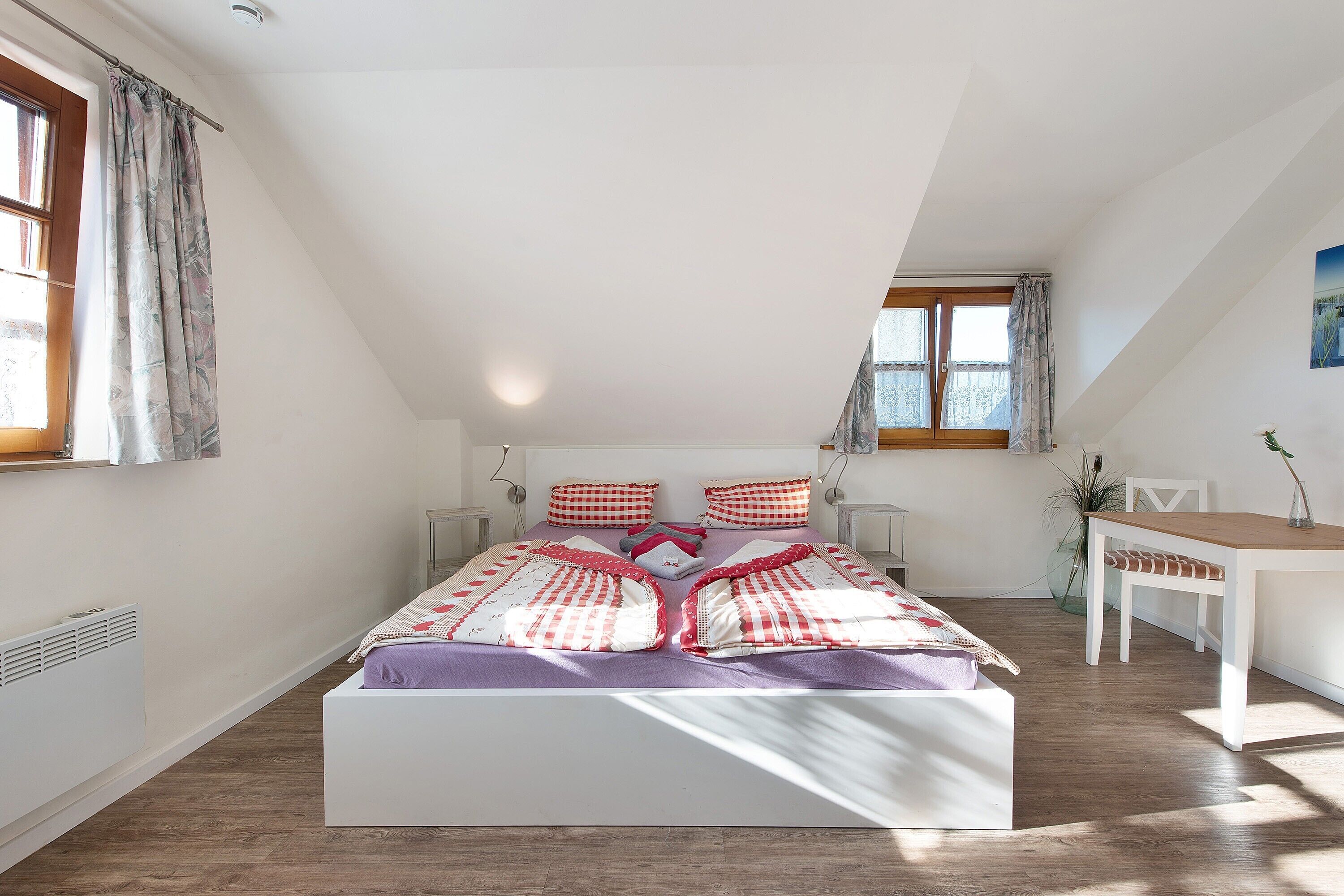 Un dormitorio con cama, escritorio y ventana.
