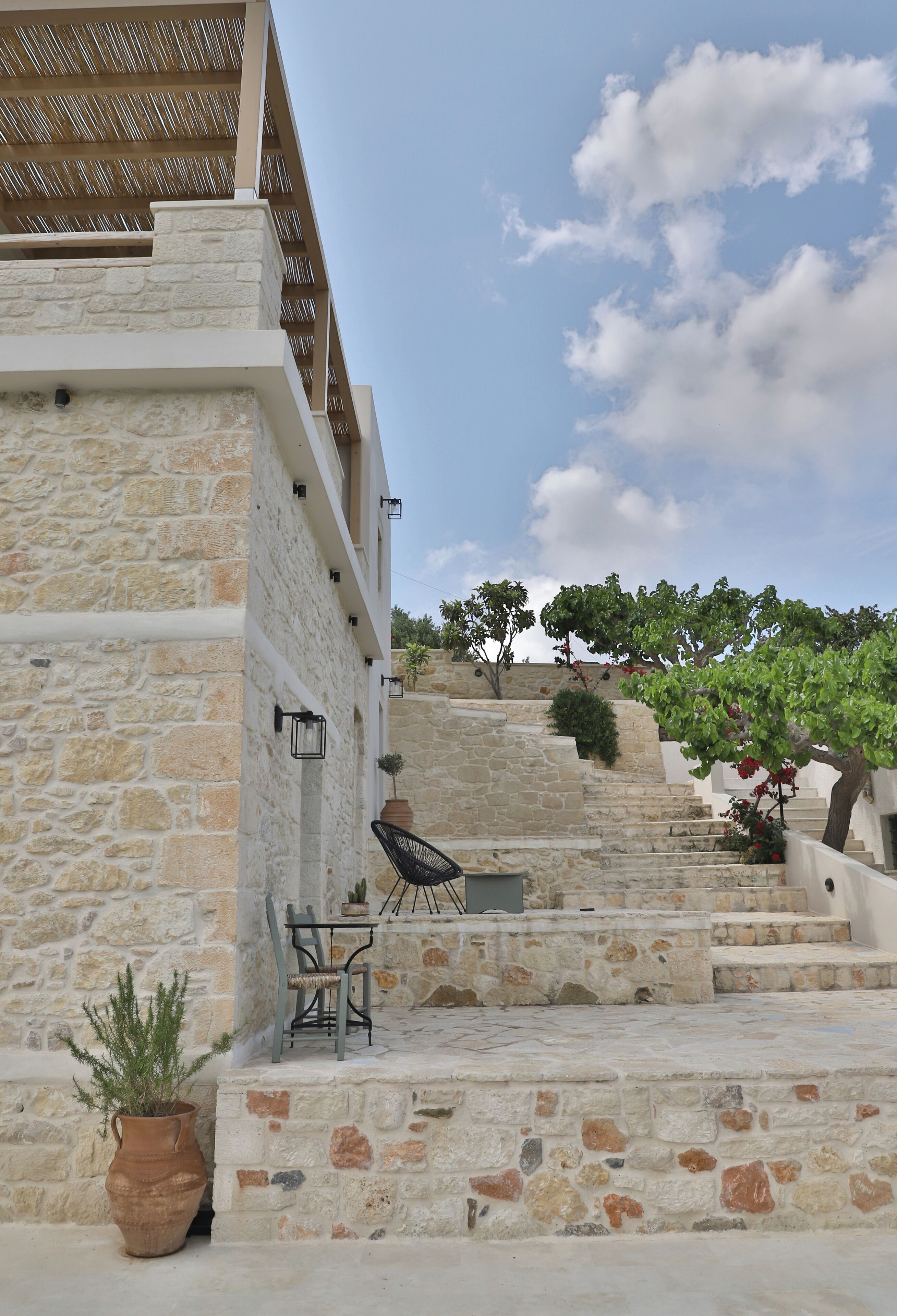 A stone staircase leading to a terrace with outdoor furniture and a potted plant.