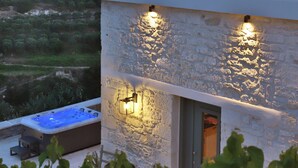 A modern building with a stone facade, a hot tub, and outdoor lighting. - Amvikas Suites in Sitia (Sitia)