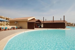 Une piscine avec des chaises longues et un bâtiment doté d’un toit plat.