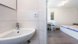 A modern bathroom with a white sink, a mirror, and a wooden floor. - Room 'Doppelzimmer Austria' with Wi-Fi (Meersburg)