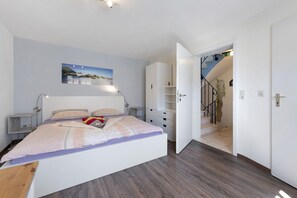 A bedroom with a bed, bedside tables, a wardrobe, and a staircase leading to another room.