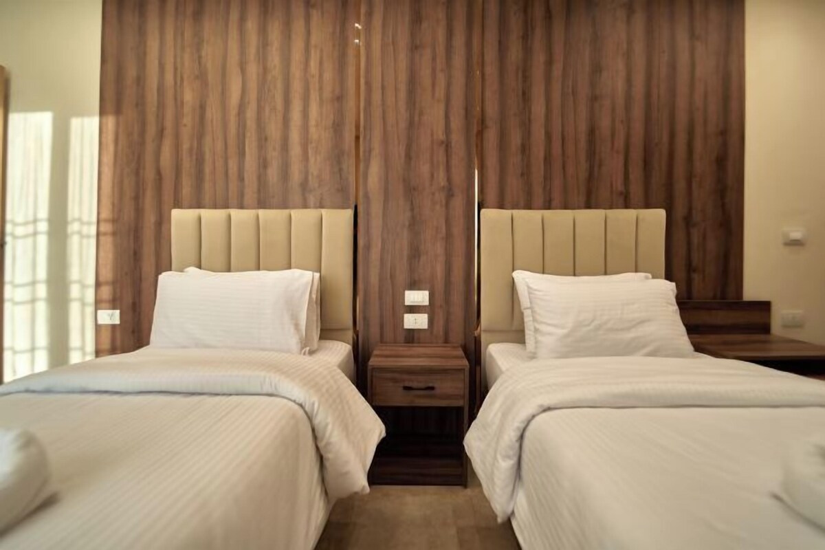 Ein Hotelzimmer mit zwei Betten, Holzvertäfelung an der Wand und Nachttischen mit Lampen.