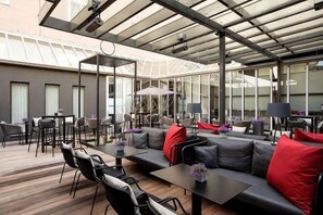 Un espace extérieur aménagé, abrité et doté d’un canapé, de chaises, de tables et de parasols.