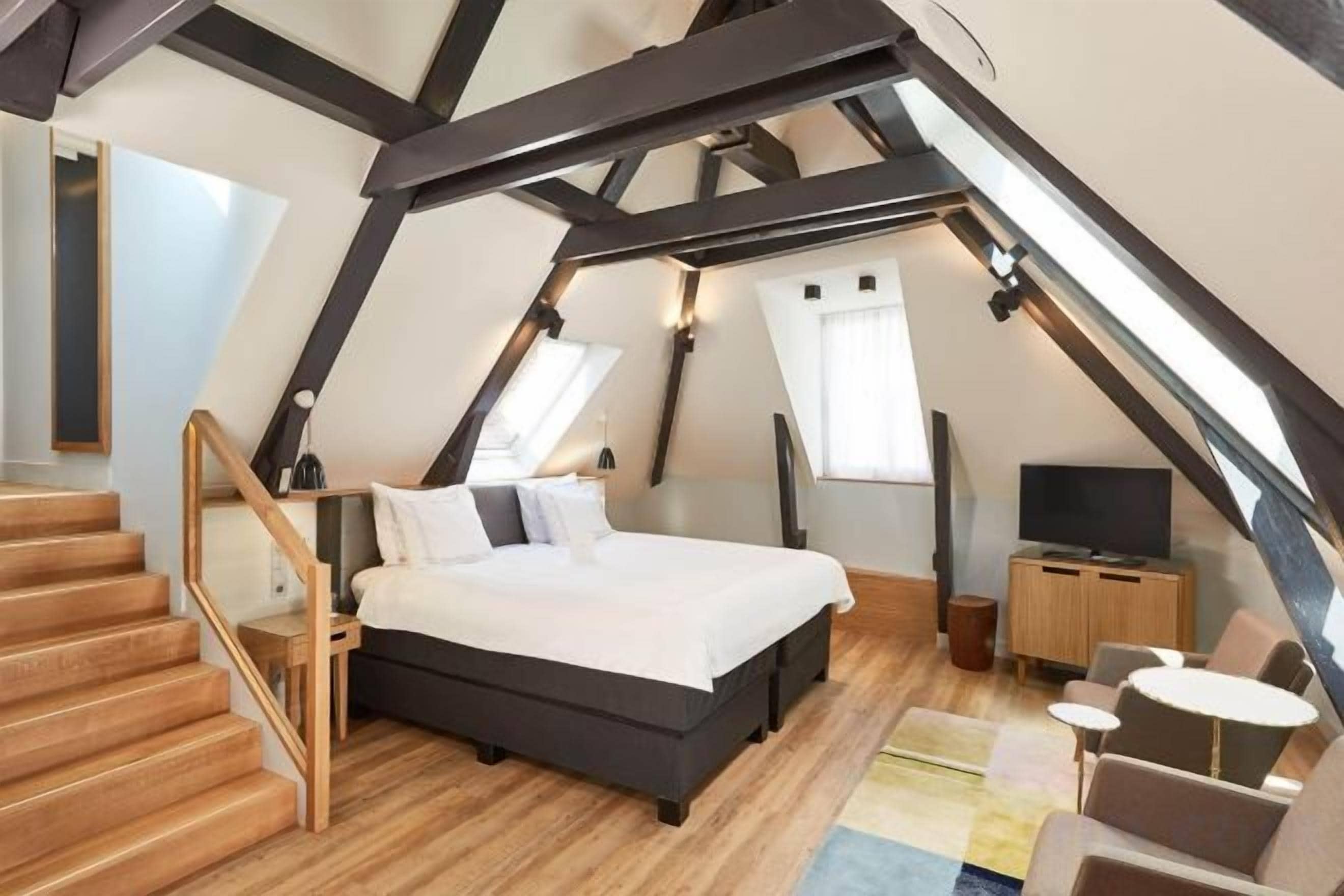 Een slaapkamer met een bed, een televisie, een bureau en een stoel.