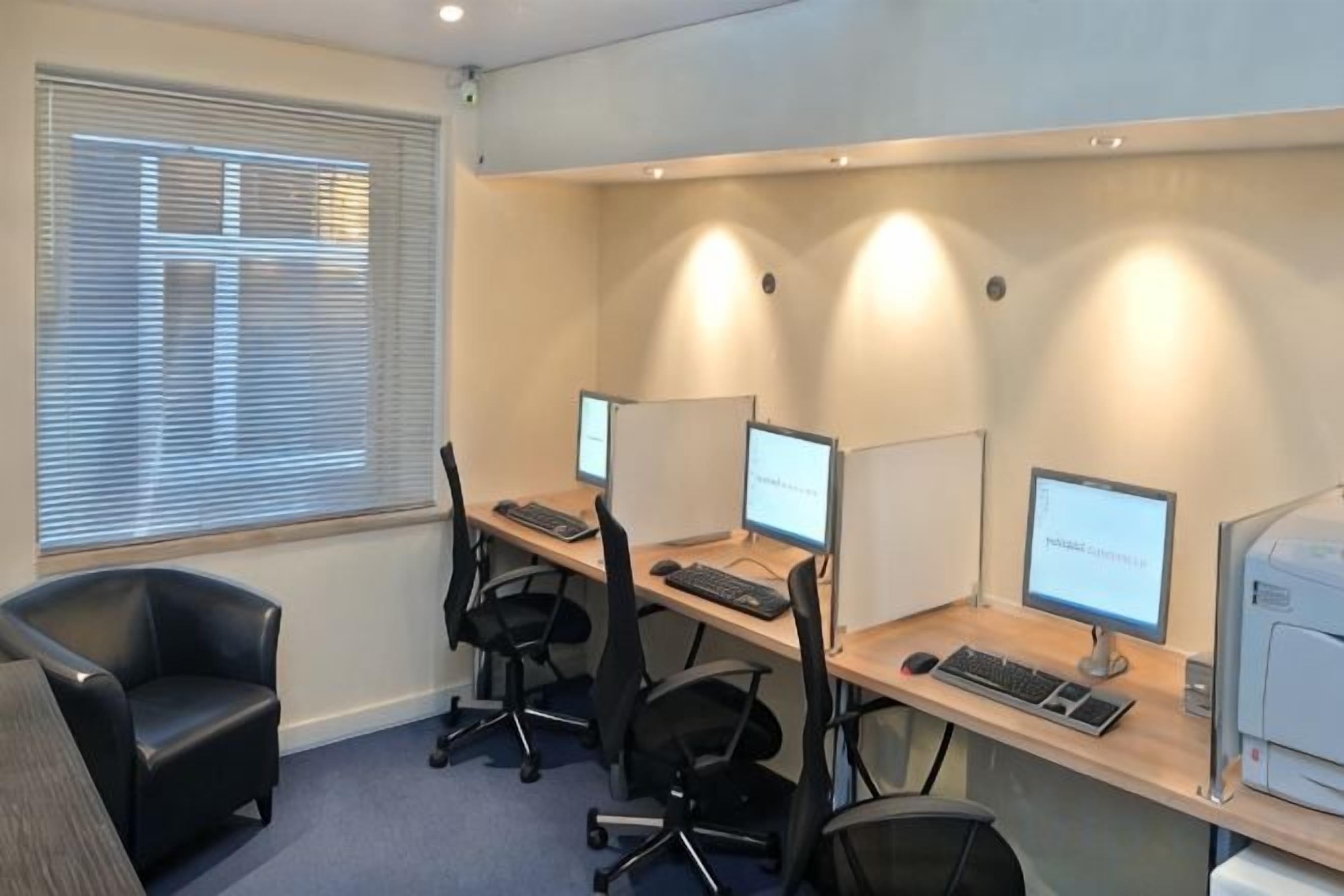 Een werkplek met kantoormeubels, computers en een printer.