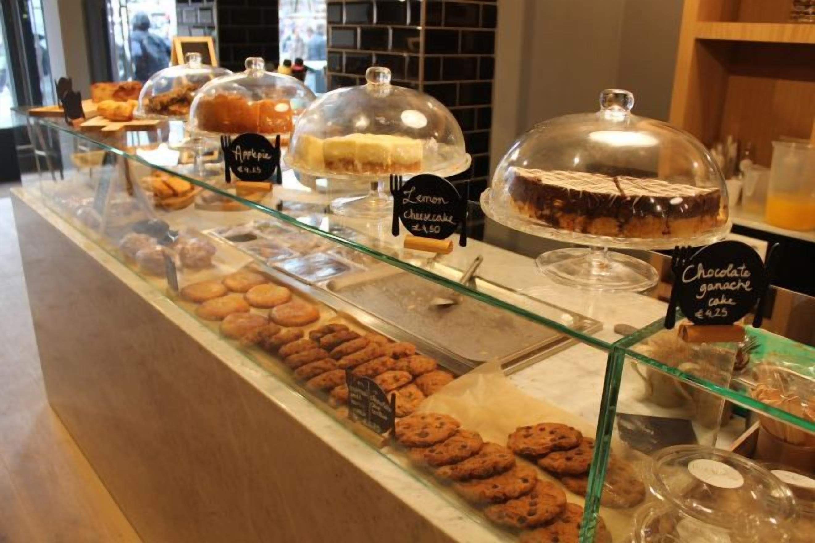 Een bakkerijdisplay met diverse gebakjes en desserts, waaronder citroen-cheesecake en chocoladetaart, geprijsd op €4,50 en €4,25 respectievelijk.
