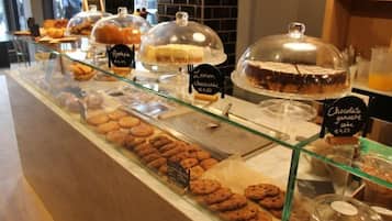 Een bakkerijdisplay met diverse gebakjes en desserts, waaronder citroen-cheesecake en chocoladetaart, geprijsd op €4,50 en €4,25 respectievelijk.