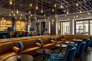 A modern lounge area with leather sofas, round tables, and hanging lights. - Swissôtel Amsterdam (Amsterdam)