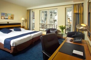 A hotel room with a bed, desk, chair, and a balcony with a view. - Swissôtel Amsterdam (Amsterdam)