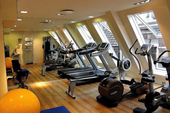 Een fitnessruimte met loopbanden, elliptische trainers en trainingsballen.