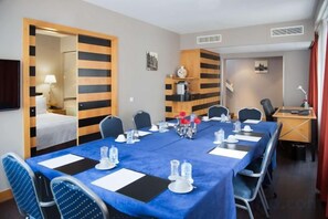 A conference room with a blue tablecloth, chairs, a coffee machine, and a desk with a computer. - Swissôtel Amsterdam (Amsterdam)