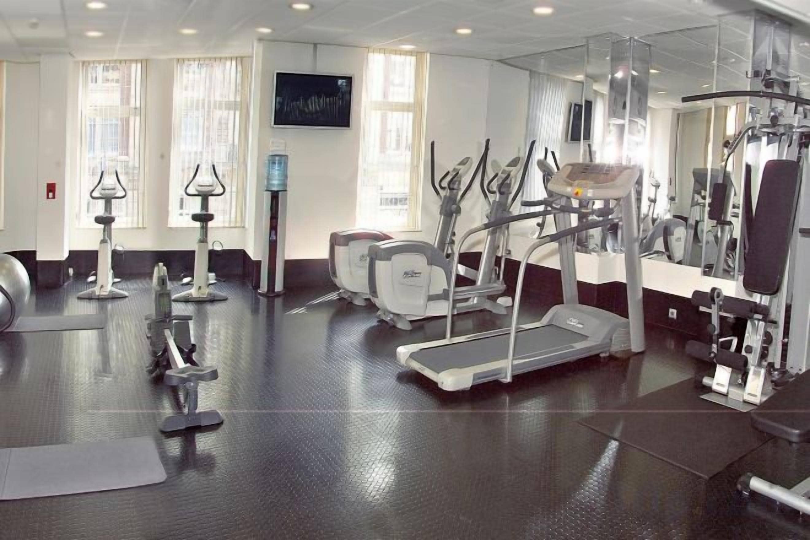 Een fitnessruimte met loopbanden, elliptische trainers en gewichten.