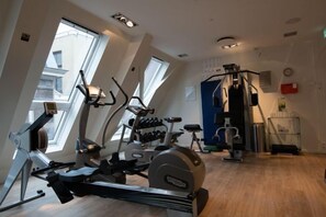 A gym with cardio machines, a weight bench, and a wall-mounted rack. - Swissôtel Amsterdam (Amsterdam)