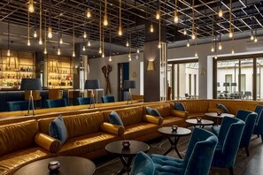 A modern lounge area with leather sofas, round tables, and blue chairs. - Swissôtel Amsterdam (Amsterdam)