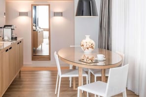 A modern dining area with a round table, white chairs, a vase, and a coffee machine. - Swissôtel Amsterdam (Amsterdam)