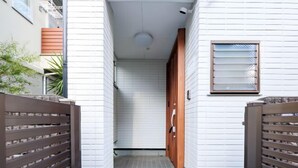 Un pasillo estrecho con paredes de azulejos blancos y una puerta de madera al final.