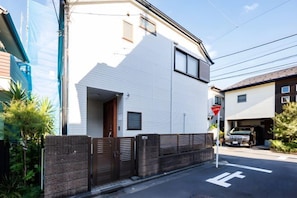 A residential building with a white exterior, a garage, and a street view. - Bliss KAMEARI (Tokyo)