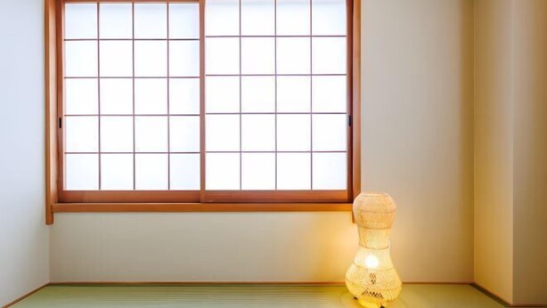 Una habitación con suelo de tatami, puerta corredera shoji y un farol japonés tradicional de papel.