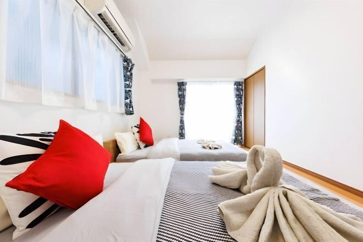 Hotellihuone, jossa on kaksi sänkyä, suuri ikkuna ja ilmastointilaite.