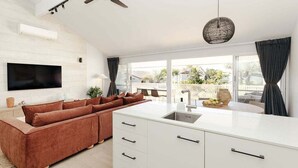 A modern kitchen with a white countertop, a built-in oven, and a large window offering a view of the outdoors. - Villa Palmera by Balmy Breaks - 100m to Beach (Noosa)