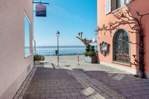 Uma trilha pavimentada que leva a um edifício com vista para o mar, um poste de luz e um portão de ferro decorativo.