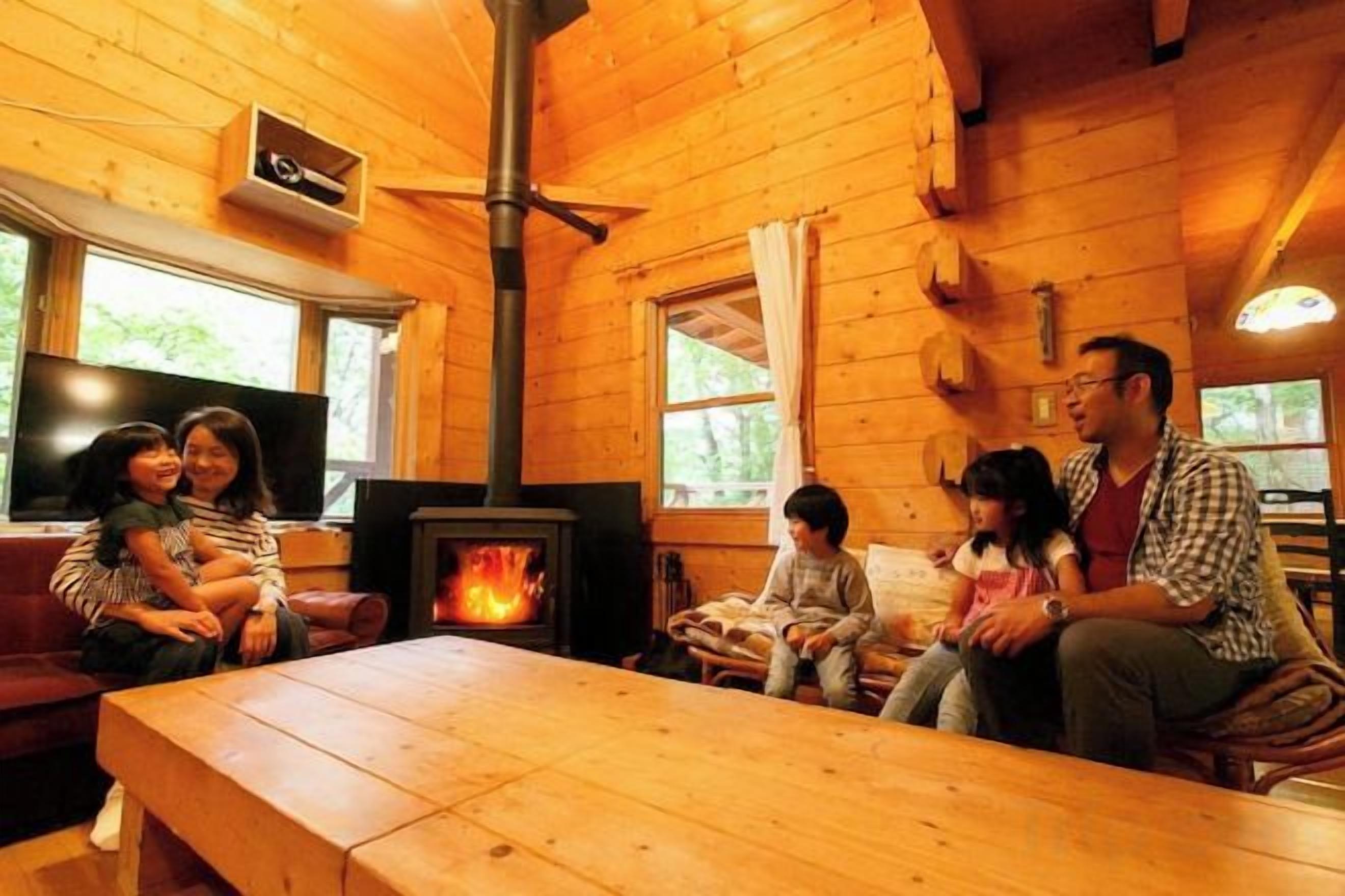 A wooden cabin interior with a fireplace, seating area, and a television.