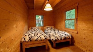 A wooden cabin room with two beds, a window, and a ceiling light. - Log House Nasu High Grand (Nasu)