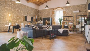 Un espacio habitable amplio con una pared de piedra, un sofá gris oscuro, una mesa de centro y un área de comedor con sillas y una mesa.