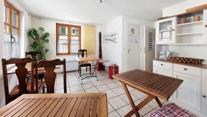 A kitchen with wooden furniture, a dining area, and a window with blinds. - Room 'Double Room Bavaria' with Wi-Fi (Meersburg)