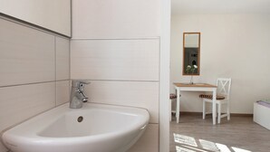 A bathroom with a white sink, a mirror, and a wooden chair. - Room 'Double Room Bavaria' with Wi-Fi (Meersburg)