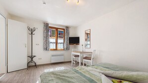 A bedroom with a bed, a desk, a chair, a television, and a coat rack. - Room 'Double Room Bavaria' with Wi-Fi (Meersburg)