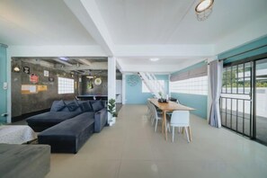 Un intérieur moderne comprenant un canapé, une table à manger, des chaises et un escalier menant à un espace extérieur.