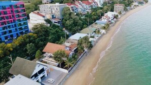 Luftaufnahme eines Küstenhotelbereichs mit Gebäuden direkt an einem Strand.