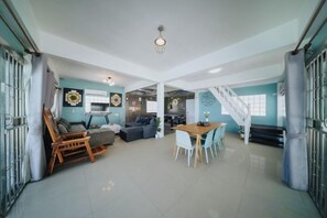 A spacious living area with a dining table, sofas, and a staircase leading to an upper level. - Gao Bee One Beach Club (Ban Chang)