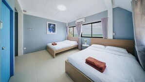 Ein Hotelzimmer mit zwei Betten, einem mit Vorhängen versehenen Fenster, einem Deckenventilator und einer Wand-Klimaanlage.