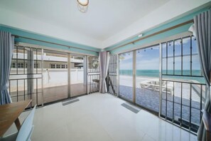 A room with a large sliding glass door leading to a balcony with a view of the beach. - Gao Bee One Beach Club (Ban Chang)
