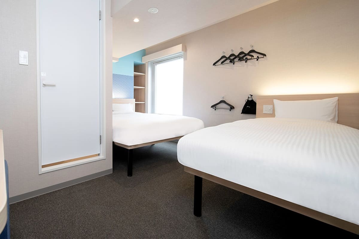 A hotel room with a bed, a bedside table, a wardrobe, and a coat rack.