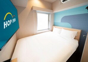Une chambre d’hôtel avec un lit, une fenêtre et un mur orné d’un motif ondulé.
