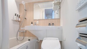 A compact bathroom with a bathtub, toilet, and a sink with a mirror above. - Hop Inn Tokyo Ueno (Tokyo)