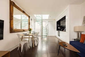 Un appartement moderne comprenant un coin repas, un canapé, une télévision et un escalier.