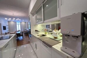 Een moderne keuken met een ingebouwd waterdispenser, een eethoek met een tafel en stoelen, en uitzicht op de woonkamer.