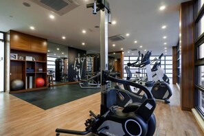 Une salle de sport équipée de matériel d’exercice, dotée d’un mur miroir et d’un plancher en bois.
